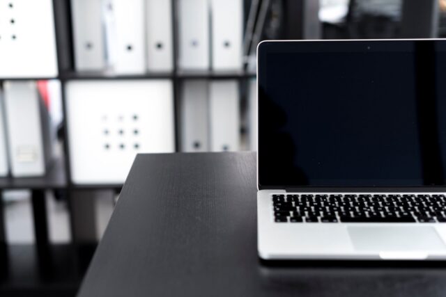 Laptop pe un birou ordonat, lângă o fereastră, într-un spațiu liniștit de lucru